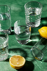 Image showing glasses with water and lemons on green background