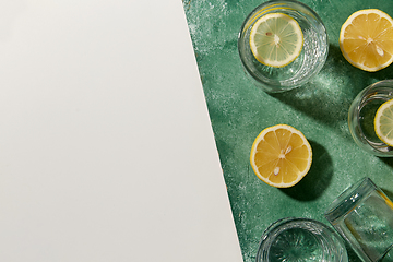 Image showing glasses with water and lemons on green background