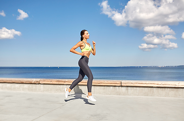 Image showing young woman running along sea promenade