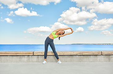 Image showing young woman doing sports and stretching outdoors