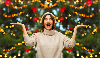 Image showing happy woman holding something over christmas tree