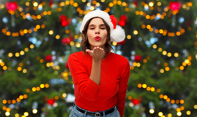 Image showing happy young woman in santa hat sending air kiss