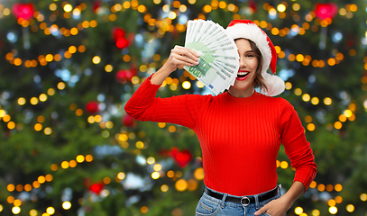 Image showing happy woman in santa hat with money on christmas