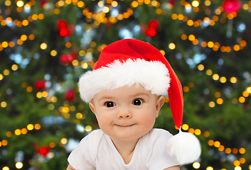 Image showing baby in santa hat over christmas tree lights