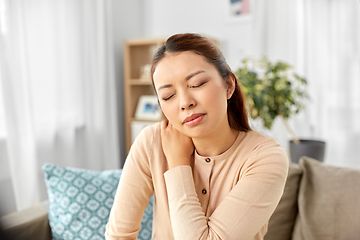 Image showing asian woman suffering from ache in neck at home