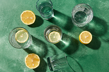 Image showing glasses with water and lemons on green background