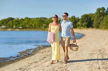 Image showing happy couple with picnic basket walking on beach