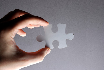 Image showing Hand holding a puzzle piece