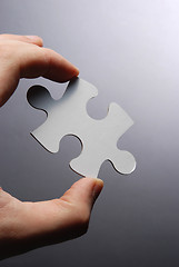 Image showing Hand holding a puzzle piece