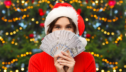 Image showing happy woman in santa hat with money on christmas