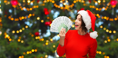 Image showing happy woman in santa hat with money on christmas