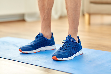 Image showing close up of male feet in sneakers on exercise mat