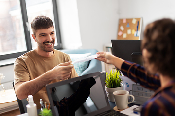 Image showing smiling man taking papers from colleague at office