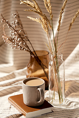 Image showing cup of coffee on book and dried flowers in vases