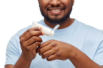 Image showing happy african man applying moisturizer to his hand