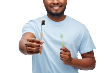 Image showing man comparing wooden and plastic toothbrushes