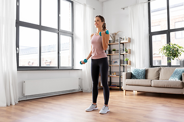 Image showing smiling young with dumbbells exercising at home