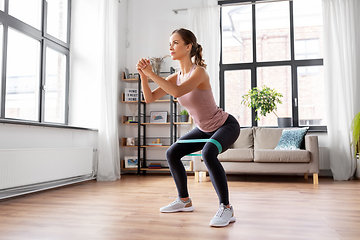 Image showing woman exercising with resistance band at home