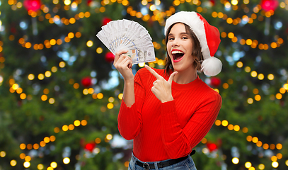 Image showing happy woman in santa hat with money on christmas