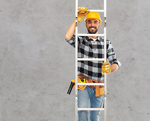 Image showing happy male builder in helmet climbing up ladder