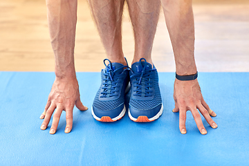 Image showing close up of male hands and feet on exercise mat