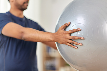 Image showing man exercising and doing squats with ball at home