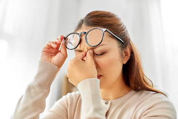 Image showing tired asian woman with glasses rubbing nose bridge