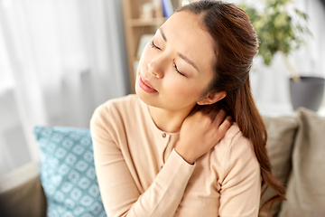 Image showing asian woman suffering from ache in neck at home