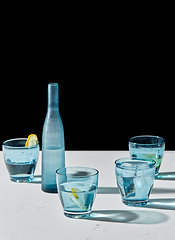 Image showing glasses with water and lemons on white background
