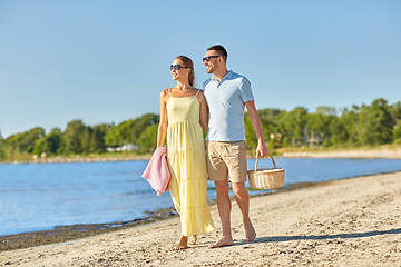 Image showing happy couple with picnic basket walking on beach