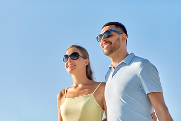 Image showing happy couple in sunglasses hugging over blue sky