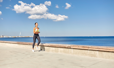 Image showing young woman running along sea promenade