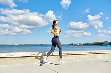 Image showing woman with headphones and smartphone running