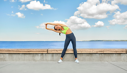 Image showing young woman doing sports and stretching outdoors