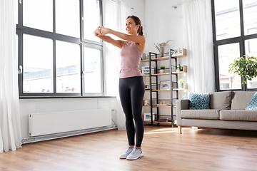 Image showing smiling young woman stretching arms at home