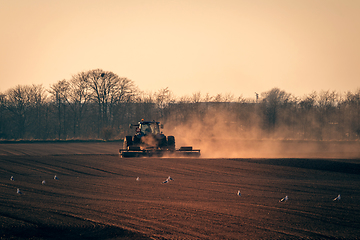 Image showing Tractor on a field in the sun with dust flying