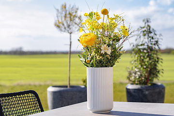 Image showing Yellow wildflowers in a white vase