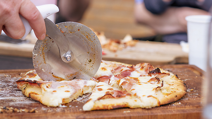 Image showing Homemade pizza being sliced on a wooden board
