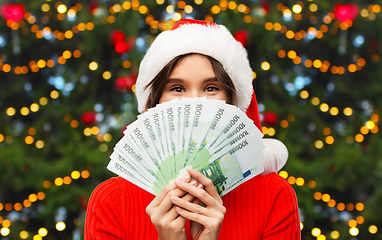 Image showing happy woman in santa hat with money on christmas