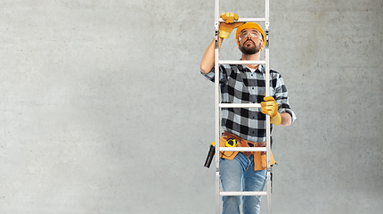 Image showing male builder in helmet climbing up ladder