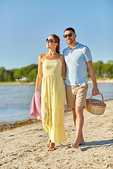 Image showing happy couple with picnic basket walking on beach