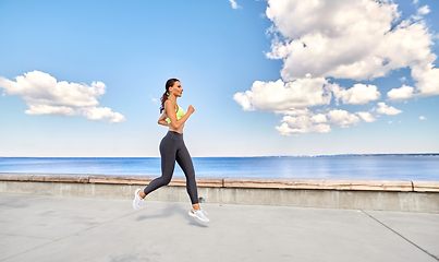 Image showing young woman running along sea promenade