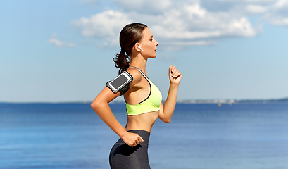 Image showing woman with earphones and smartphone running