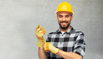 Image showing happy male worker or builder in helmet and gloves