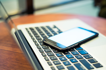 Image showing Cellphone on laptop computer in coffee shop