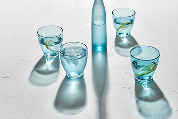 Image showing glasses with water and lemons on white background