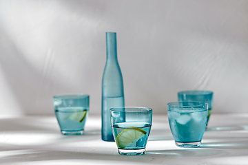 Image showing glasses with water and lemons on white background