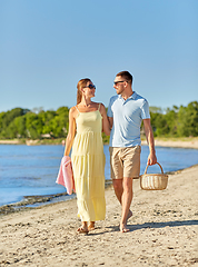 Image showing happy couple with picnic basket walking on beach