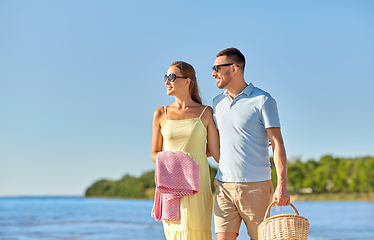 Image showing happy couple with picnic basket walking on beach