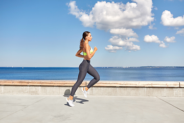 Image showing young woman running along sea promenade